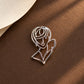 Detail shot of Tie Shop Silver Abstract Line Art Face Brooch on a warm brown surface, an elegant artistic metallic brooch. صورة دقيقة لـ بروش وجه المرأة الفني الفضي من تاي شوب على خلفية بنية دافئة، بروش معدني راقي. إكسسوارات الحجاب من تاى شوب 