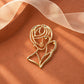 Close-up of Tie Shop Gold Abstract Line Art Face Brooch displayed on a terracotta surface with white organza ribbon. صورة مقربة لـ بروش وجه المرأة الفني الذهبي من تاي شوب على سطح ترابي   وشريط أورجانزا. بروش للحجاب والملابس من تاى شوب 