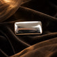 Close-up of Tie Shop Minimalist Silver Rectangular Brooch with smooth polished finish, a sleek metallic accessory for abayas, suits, and hijabs. صورة مقربة لـ بروش فضي مستطيل بتصميم مينيماليست ناعم من تاي شوب، اكسسوار معدني عصري للعبايات والبدلات والحجاب.