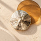 Close-up of Tie Shop Textured Sunburst Round Gold Brooch, a luxury metallic accessory designed for abayas, dresses, and hijabs. صورة مقربة لـ بروش ذهبي دائري بتصميم شعاعي من تاي شوب، اكسسوار معدني فاخر للعبايات والفساتين والحجاب.