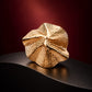 Close-up of Tie Shop Sculptural Shell Gold Brooch featuring a textured 3D wave pattern, a luxury accessory for abayas and formal dresses. صورة مقربة لـ بروش ذهبي بتصميم صدفة تجريدية من تاي شوب ببروز ثلاثي الأبعاد ونقش بارز، اكسسوار فاخر للعبايات والفساتين.