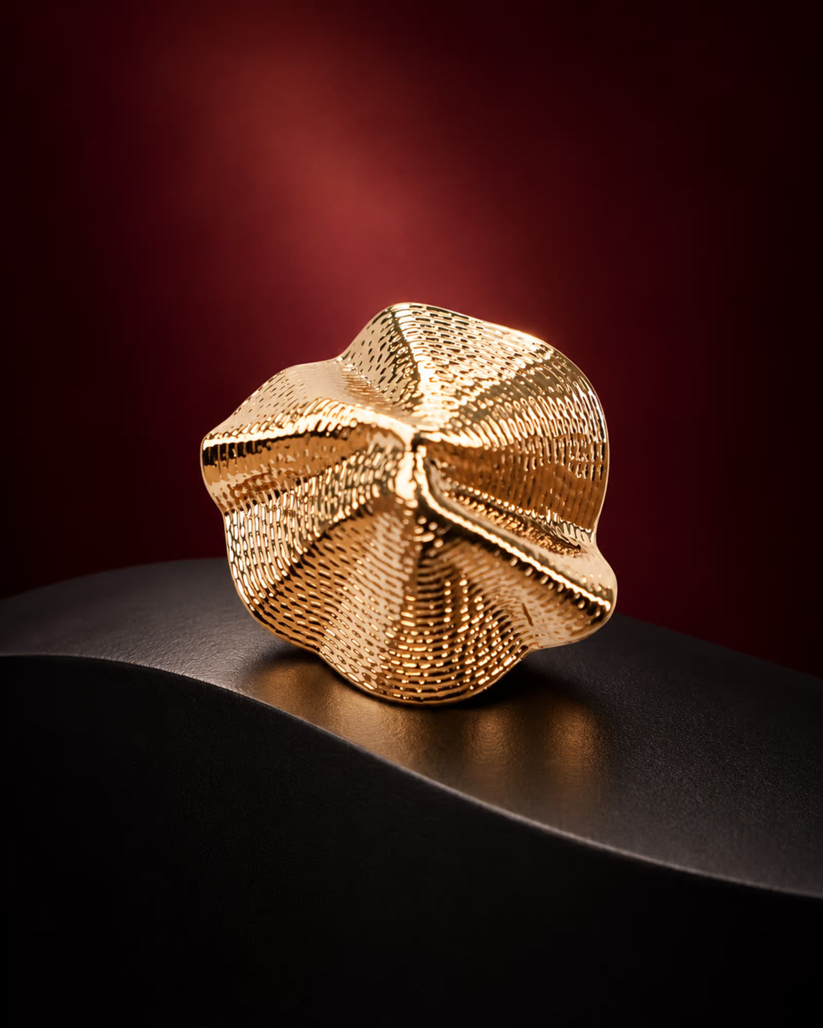 Close-up of Tie Shop Sculptural Shell Gold Brooch featuring a textured 3D wave pattern, a luxury accessory for abayas and formal dresses. صورة مقربة لـ بروش ذهبي بتصميم صدفة تجريدية من تاي شوب ببروز ثلاثي الأبعاد ونقش بارز، اكسسوار فاخر للعبايات والفساتين.