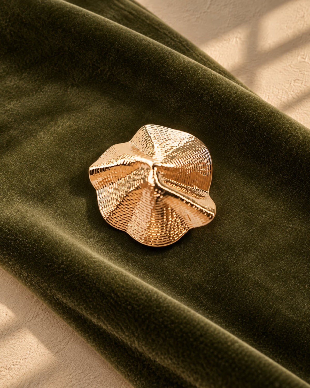 Detailed view of Tie Shop Sculptural Shell Gold Brooch, a statement metallic pin designed for formal dresses, outfits, and hijabs. عرض تفصيلي لـ بروش ذهبي بتصميم صدفة تجريدية من تاي شوب، دبوس معدني مميز لتزيين فساتين السهرة والحجاب.
