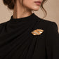 Model wearing a black formal draped dress styled with Tie Shop Abstract Gold Wave Leaf Brooch, a luxury brooch accessory for women's hijab and outfits. موديل ترتدي فستان أسود أنيق مزين بـ بروش نسائي من تاي شوب بتصميم ورق شجر ذهبي مموج، إكسسوار أنيق للحجاب والملابس.
